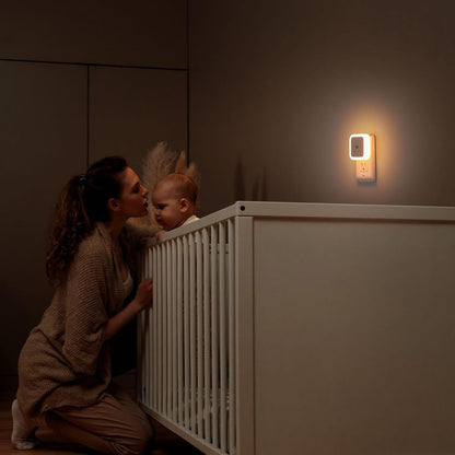 White plug-in dusk to dawn LED night light in a wall outlet, alternate view 1