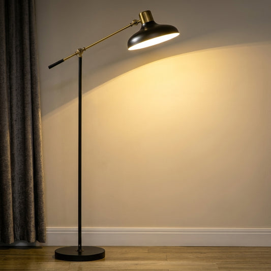 Swing arm floor lamp in black and brass — black dome shade with brass cap on an adjustable brass balance arm, thin black pole and round black base, lit against a wall